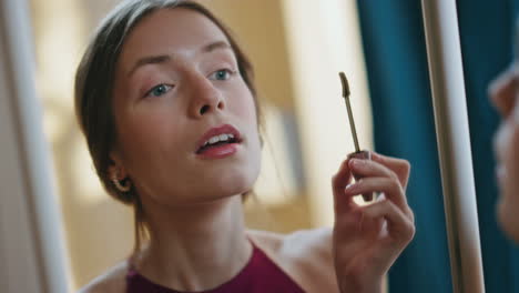Closeup girl using mascara applying on eyelashes. Woman reflection in mirror
