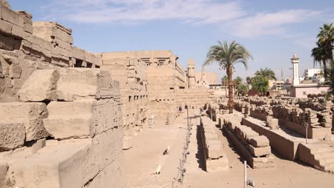 panning shot of the ruins of ancient temple of luxor with a mosque and minaret