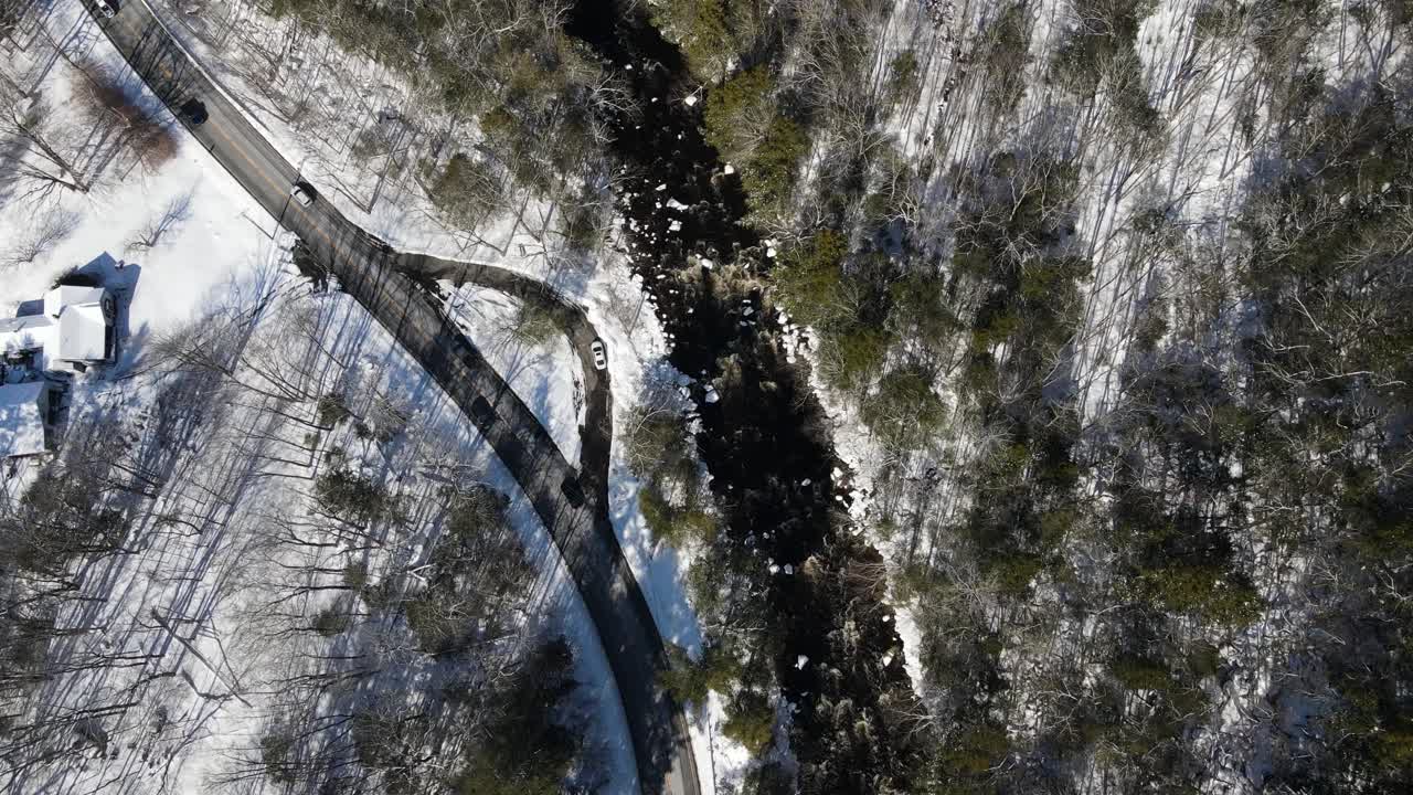 Birds-eye view of winding road and rushing river in a winter climate