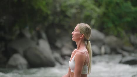 Atractiva-Mujer-Rubia-Respirando-Aire-Fresco-Mientras-Se-Sienta-En-Posición-De-Loto,-Yoga