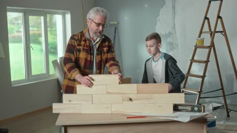 grandfather and grandchild building a wooden wall