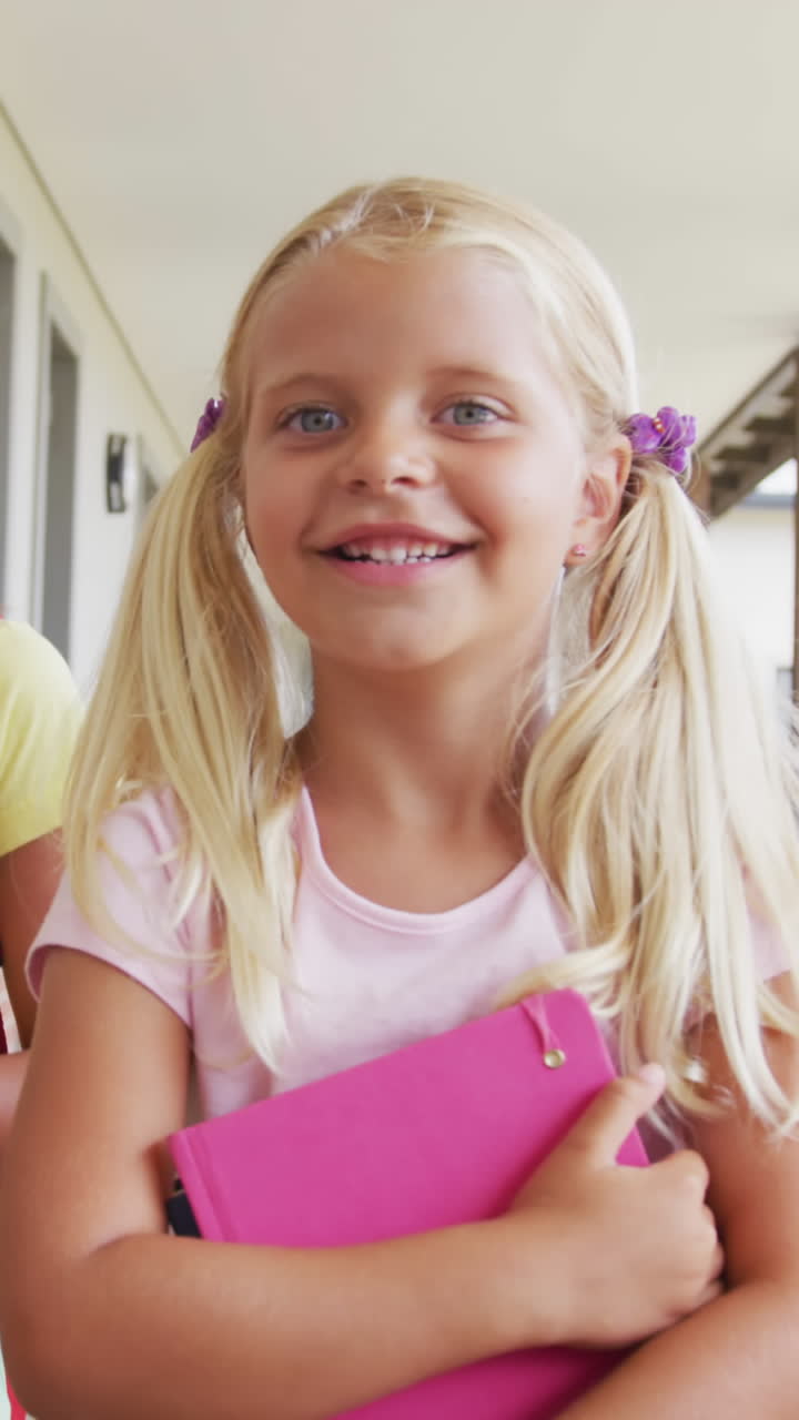 Video: Fröhliche Mädchen unterschiedlicher Herkunft gehen auf einem Schulflur und unterhalten sich.