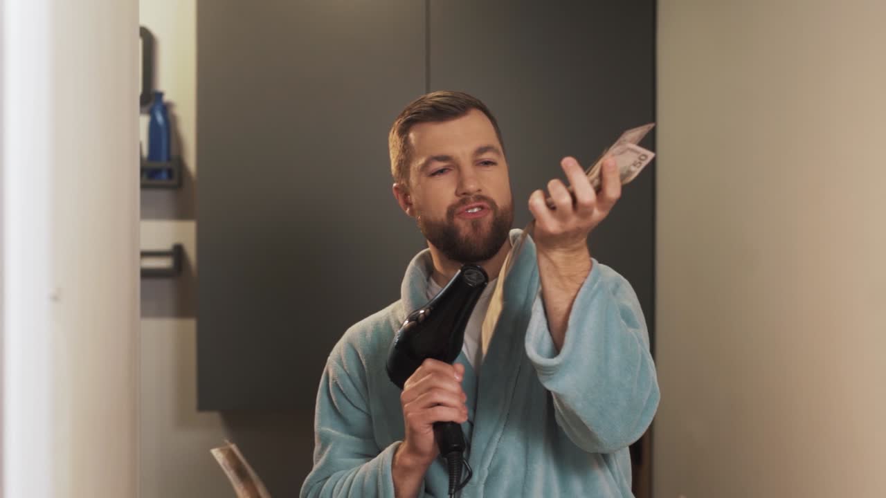 기쁨에 헤어 드라이어로 돈을 부는 젊은 남자의 초상화