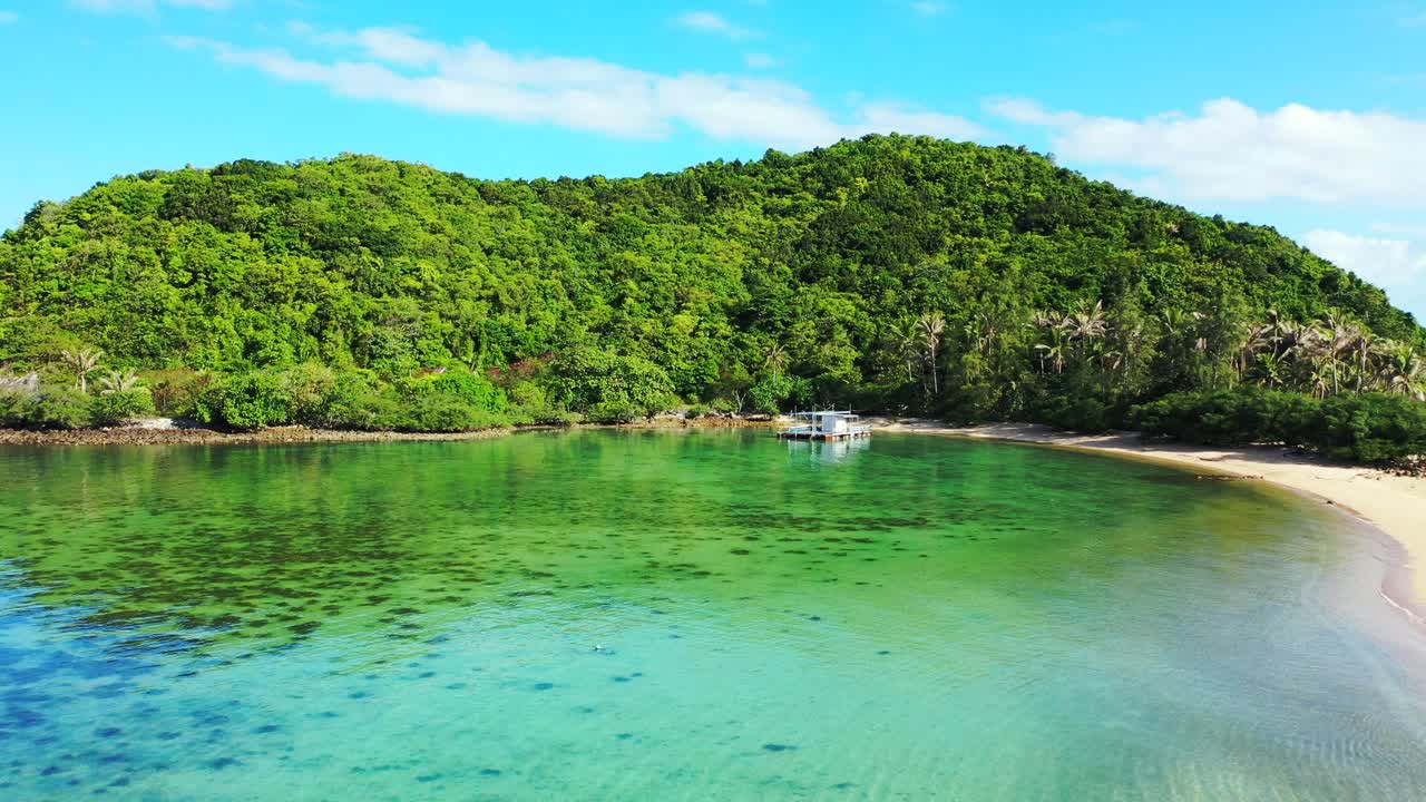 흰 구름이 있는 밝은 푸른 하늘 아래 열대 섬의 바위투성이 해안선과 모래 해변을 씻는 크리스탈 에메랄드 물이 있는 고요한 만