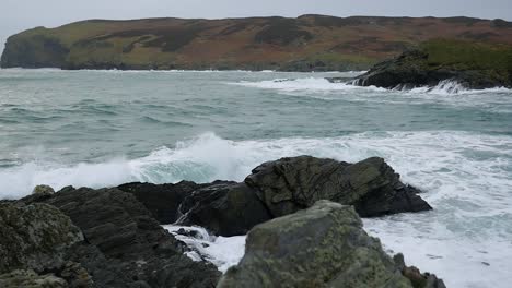 olas rompiendo sobre rocas en la pantorrilla del hombre, isla de man