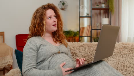 pregnant woman browsing baby products on laptop smiling with excitement emotional anticipation
