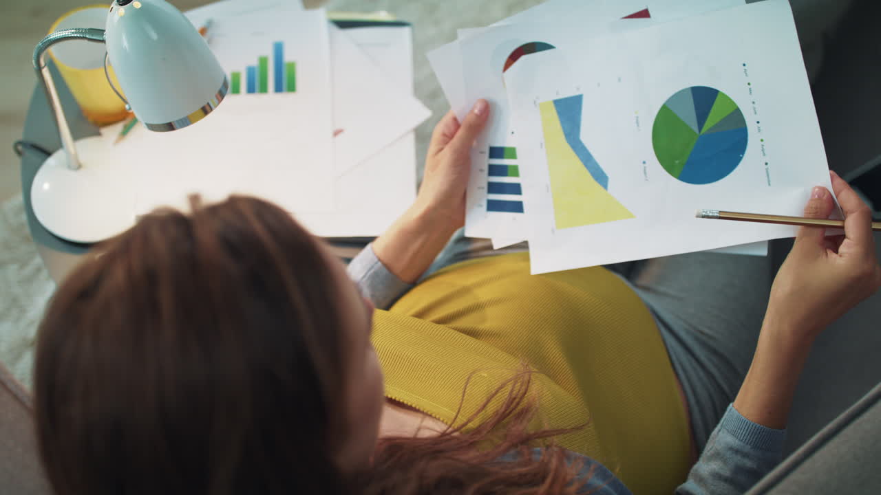 vista de arriba de una mujer embarazada trabajando con una tabla gráfica en casa.