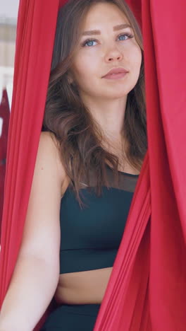 beautiful relaxed women sit in fly yoga hammocks and practice meditation holding fingers in mudra position closeup