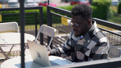 hombre trabajando en una computadora portátil en un café al aire libre