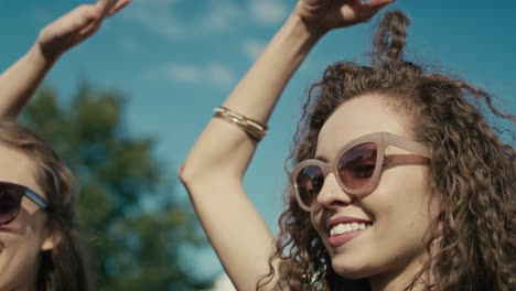 cámara rastreando sonriente joven mujer caucásica con cabello rizado bailando en un festival de música entre amigos.