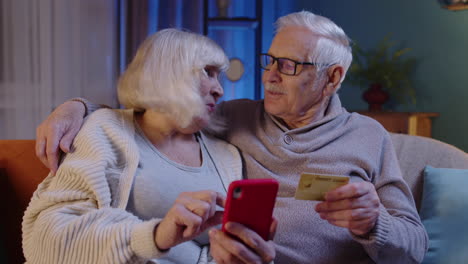 Senior-grandmother-granfather-with-mobile-phone-at-home-making-online-shopping-with-credit-bank-card