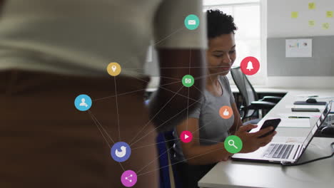 animation of network of digital icons over biracial woman greeting her colleague at office