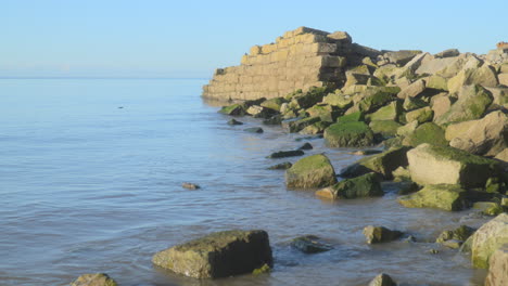 Old-ruins-on-shoreline-bathed-in-early-morning-autumn-sunlight-with-slow-rise