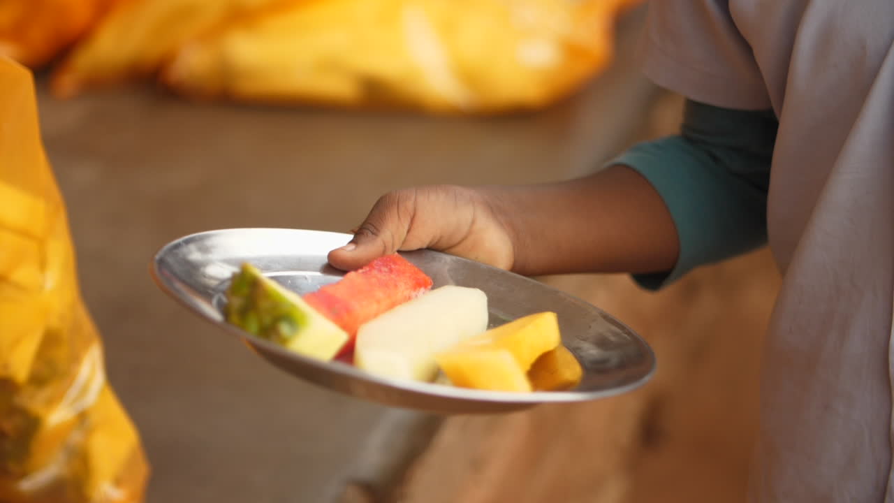 joven estudiante africano recibe fruta en un plato para el programa de almuerzo