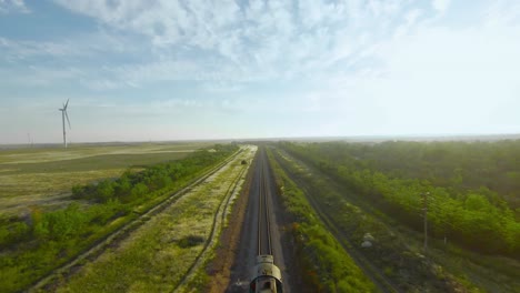 vista aérea de un tren en una línea ferroviaria a través de un paisaje rural con turbinas eólicas