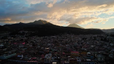 drone aerial view of urban colonial cityscape near two volcanos during golden hour sunset dusk in quetzaltenango xela guatemala