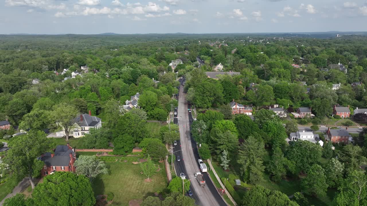 Traffic on street in luxury mansions of green neighborhood in america. Aerial forward wide shot. Forest trees on cloudy spring day. Panorama view.