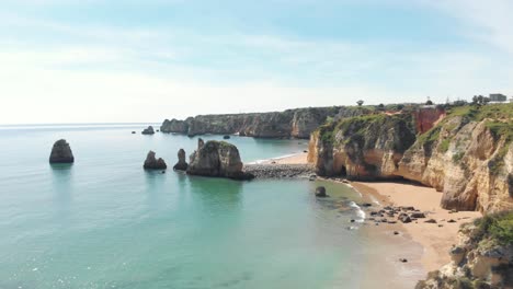 Slide-view-over-empty-Pinhão-Beach-in-Lagos-Coastline,-Algarve,-Portugal---Aerial-wide-slide-overview-shot