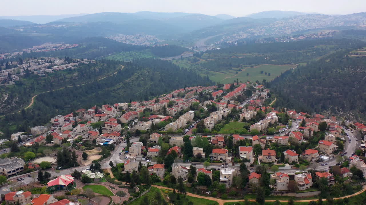 Town with Red rooftops surrounded by forest and mountains- aerial