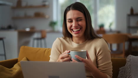 Woman laughing while using laptop at home