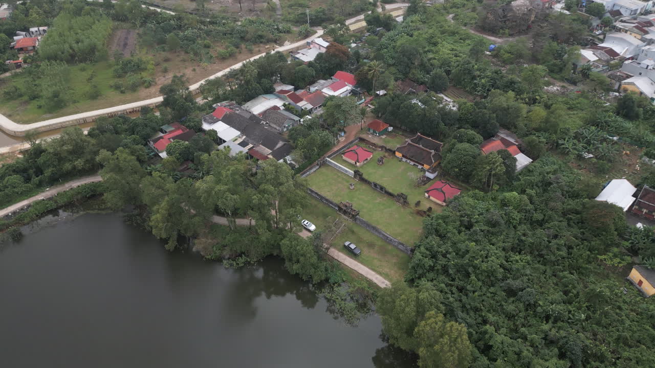 4K aerial daytime view of a Vietnamese temple complex surrounded by trees and water