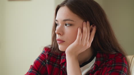 young woman with long brown hair looks away thoughtfully.