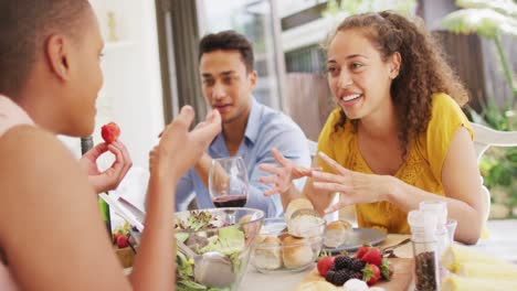 Group-of-diverse-male-and-female-friends-laughing-at-dinner-party-on-patio