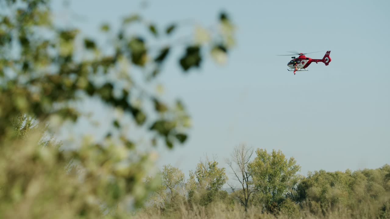 멀리 날아가는 구조 헬리콥터 - 전경 화창한 날의 녹색 잎 - 와이드 샷 - 슬로모션