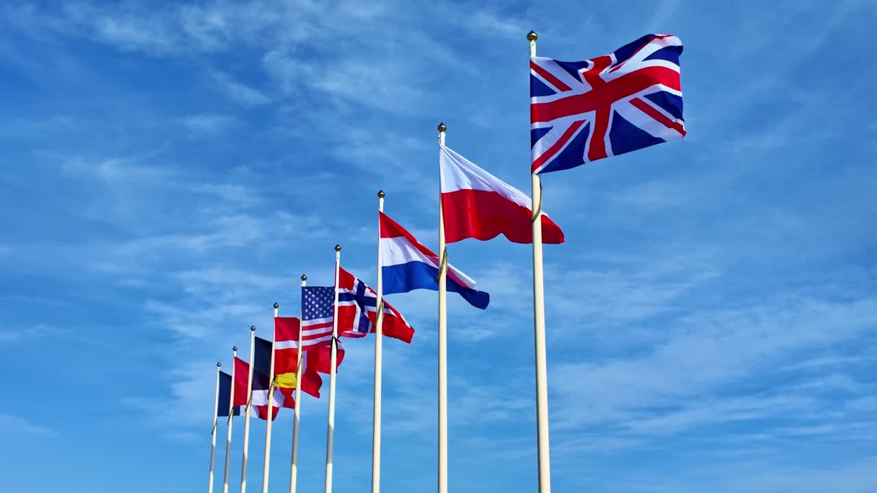 Line of allied flags fluttering in unity under a beautiful bright blue sky.