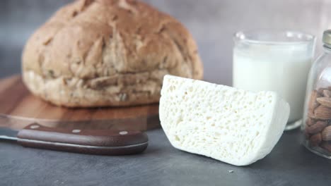 hand holding a slice of cheese next to bread and milk