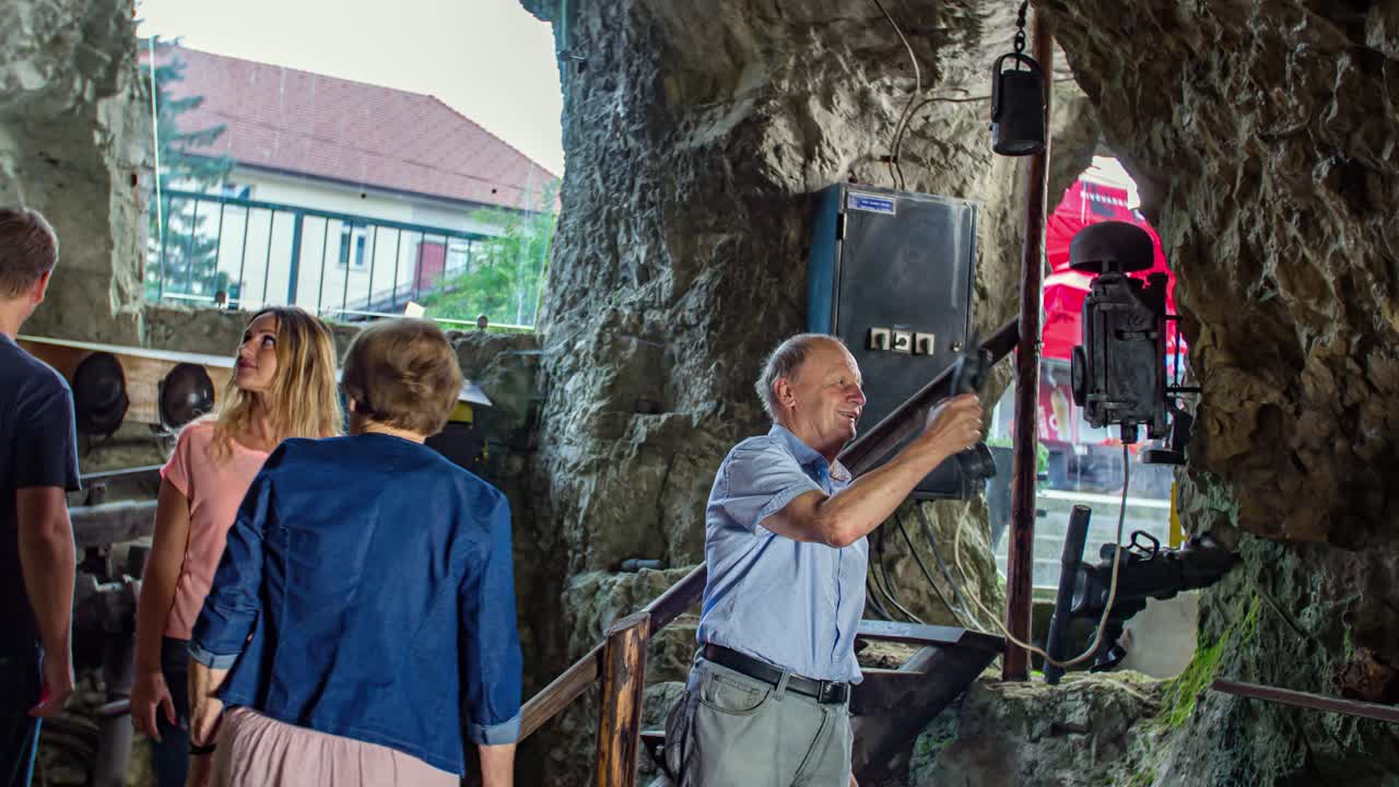 An elderly looking at an old telephone on the wall