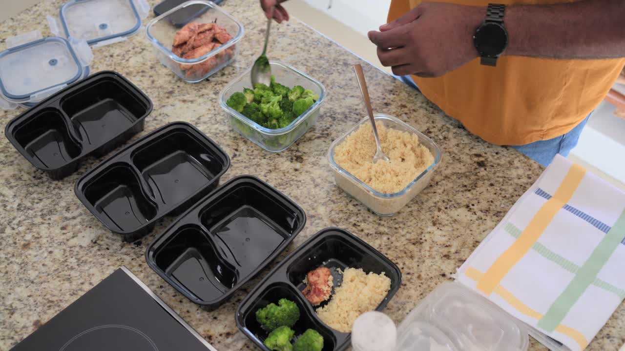 Man plaatst vier maaltijdboxen voor de lunch, schept granen op, voegt eiwitten en broccoli toe, met ruimte voor tekst.