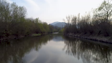 aerial drone shot of a river with reflections and mountains in the background, 4k uhd