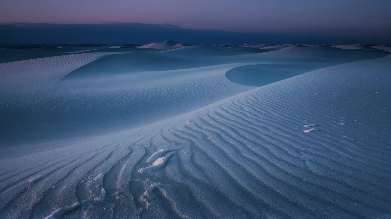 Moving camera forward surveying sand dune field at dusk, revealing ripple patterns and warm horizon