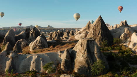 reveal shot flying above the rock formations of goreme cappadocia following the hot air balloons