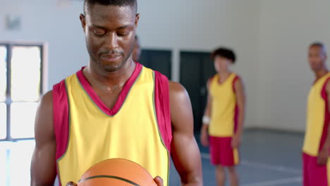 focused african american man holding a basketball in a gym