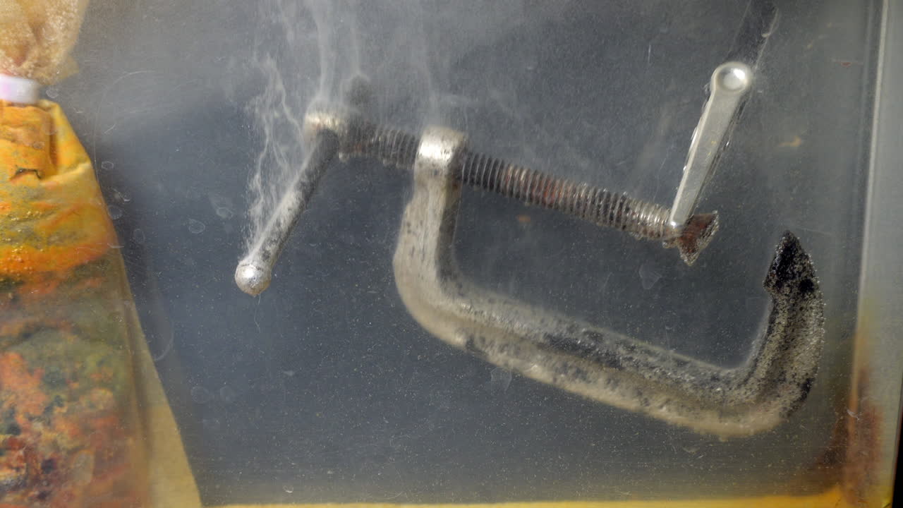 C-clamp is cleaned with electrolysis, replacing rust with new silvery metal