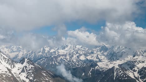 air flight through mountain clouds over beautiful snow-capped peaks of mountains and glaciers.