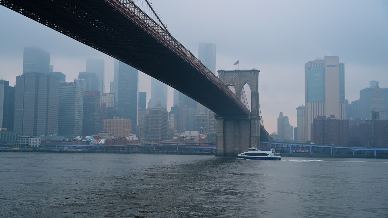 New York, USA, 25 dicembre 2025: Prospettiva del Ponte di Brooklyn dal livello dell'acqua con un traghetto