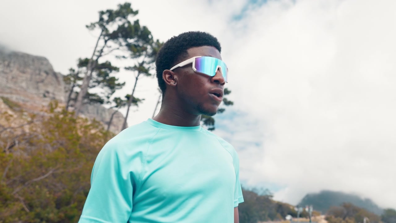 Young Male Athlete Putting On Sunglasses Before Running Outdoors