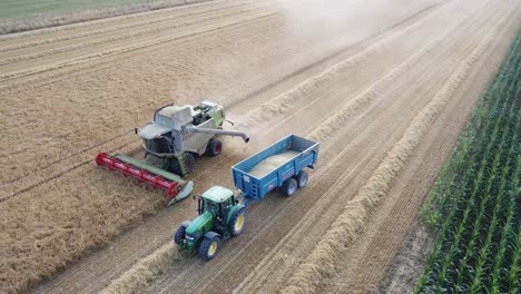 Eine-Filmische-4K-Drohnenaufnahme-Eines-Mähdreschers-Und-Eines-Traktors-Bei-Der-Ernte-Eines-Feldes-In-Frankreich,-Die-Die-Landwirtschaft-Mit-Einer-Epischen-Aussicht-Und-Dramatischem-Staub-Zeigt