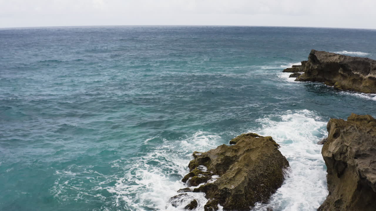 olas espumosas chocando contra las rocas en la playa de la poza del obispo en arecibo, puerto rico - toma aérea de drones