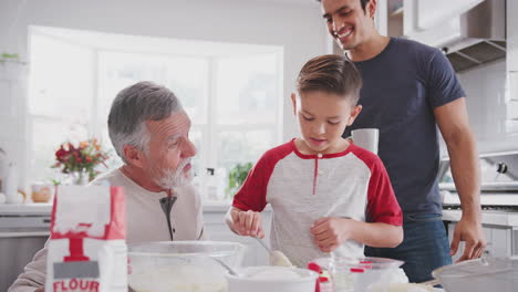 Pre-teen-Hispanic-boy-baking-with-grandfather-and-father-in-the-kitchen-filling-cake-forms,-close-up