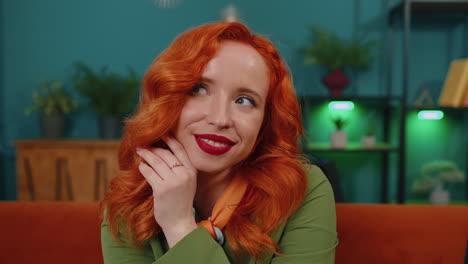 Close-up-of-happy-beautiful-teenager-redhead-ginger-woman-smiling-looking-at-camera-at-home-on-couch