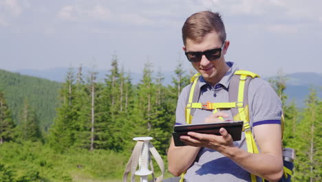 a man on a hike uses a tablet