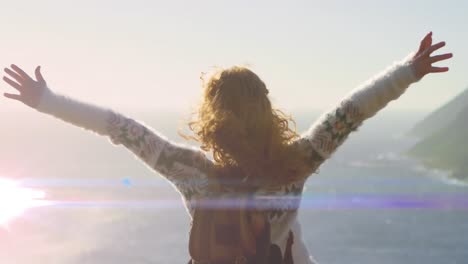 Animation-of-light-trails-over-caucasian-woman-with-arms-outstretched-on-beach