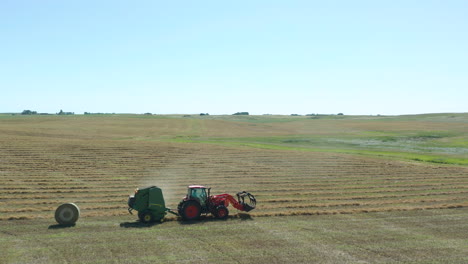 side tracking view of a tractor dropping a bale of hay during the harvesting season