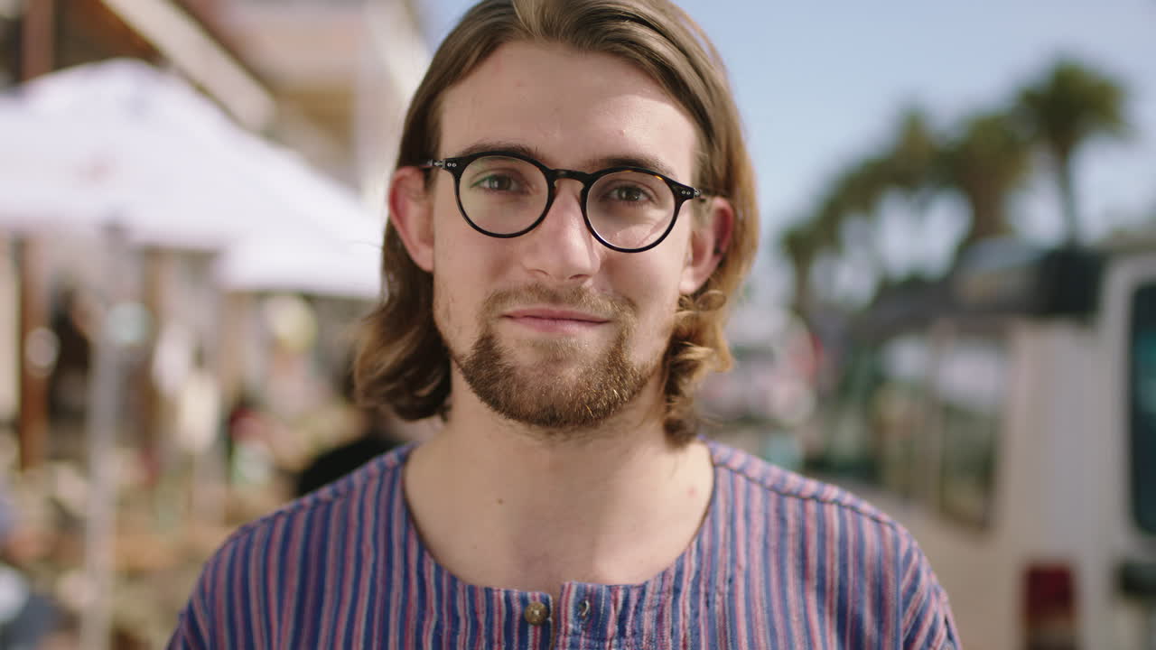 ritratto di un attraente uomo geek che sorride fiducioso sulla spiaggia