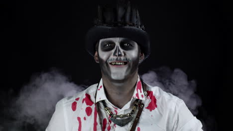 sinister man with skeleton makeup opening his mouth and showing dirty black teeth smile. halloween