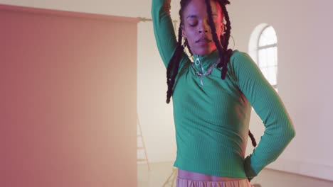 portrait of biracial female dancer dancing in dance studio, slow motion